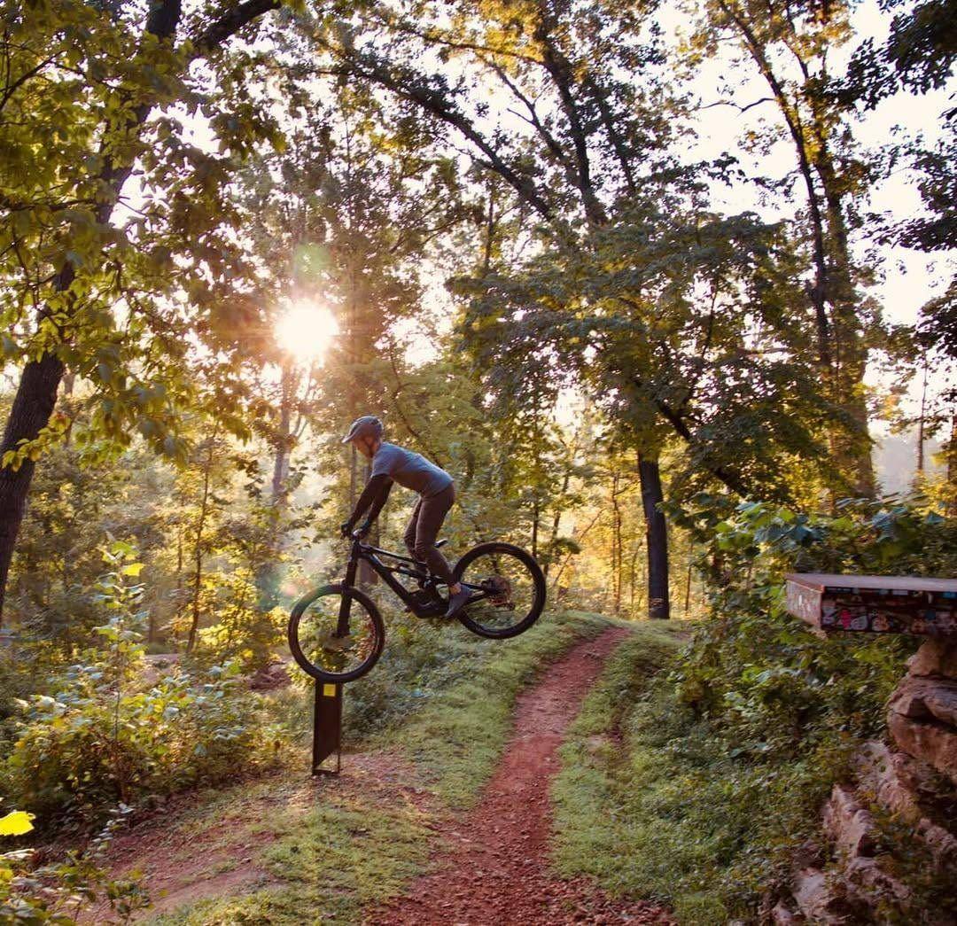 Mountain biker catching airtime on Bentonville singletrack at golden hour
